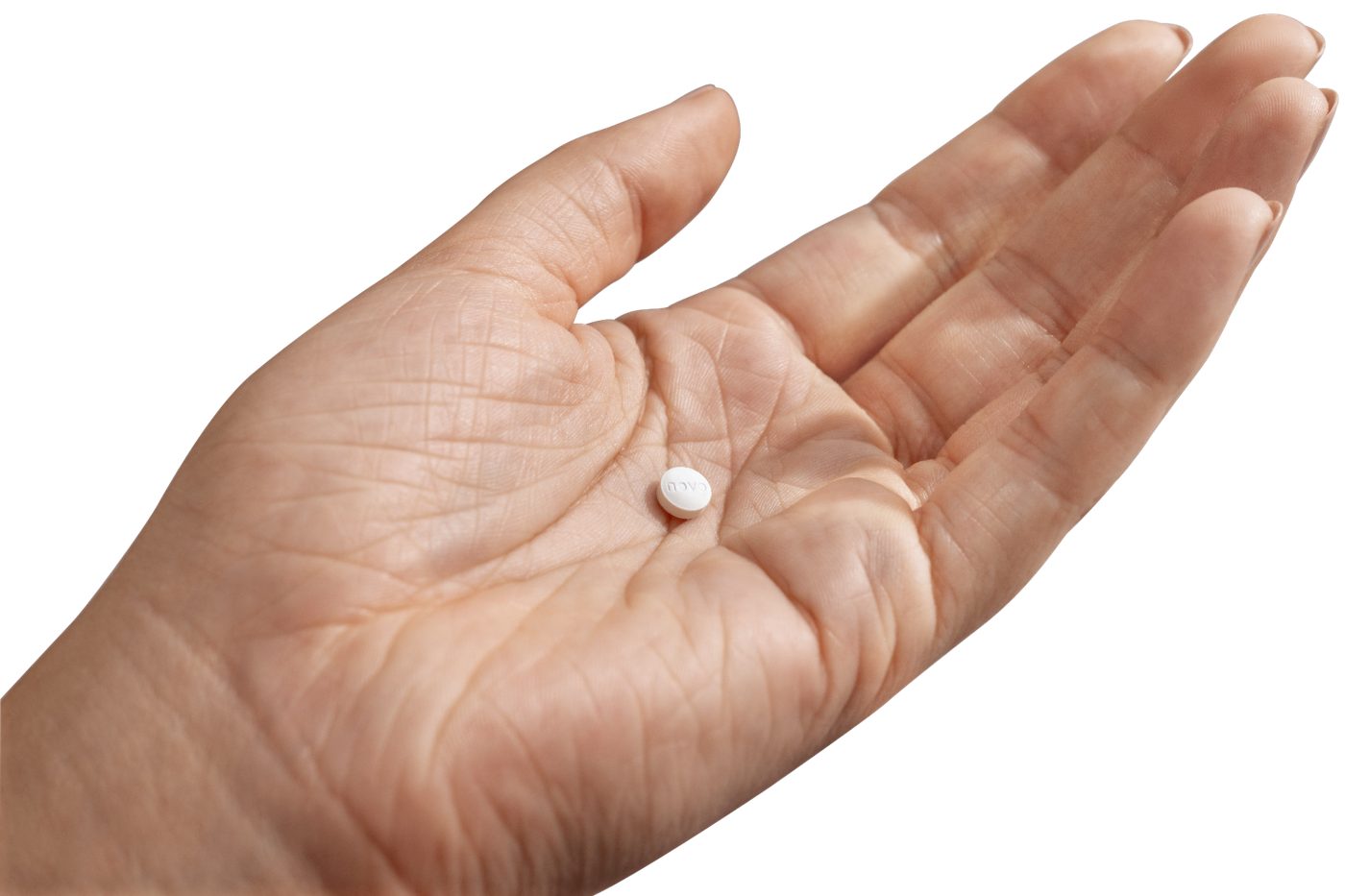 A single small white tablet resting on an open palm